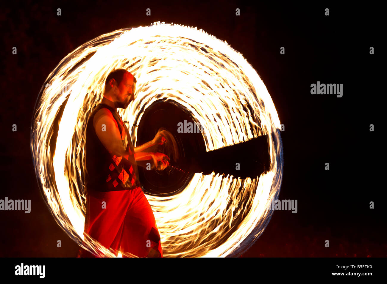Firepoise uomo artista prestazioni di visualizzazione di modelli d'incendio con sfere di poi giocare con il fuoco Foto Stock