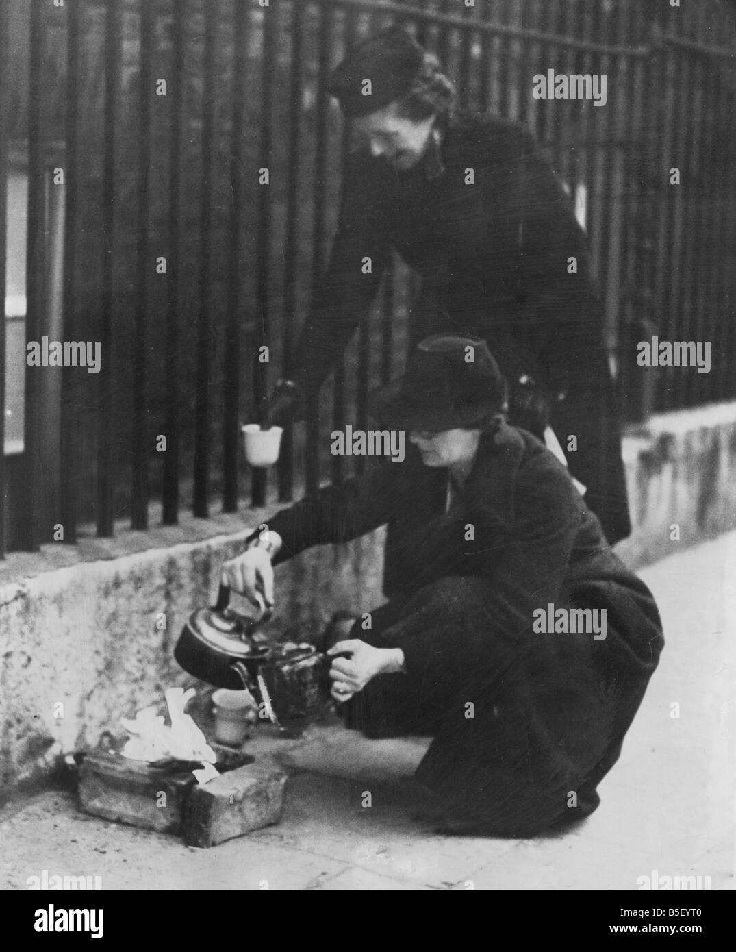 Le donne residenti di Londra facendo di se stessi un po' di fuoco per la mattinata una tazza di tè in strada il giorno dopo un raid aereo può Foto Stock
