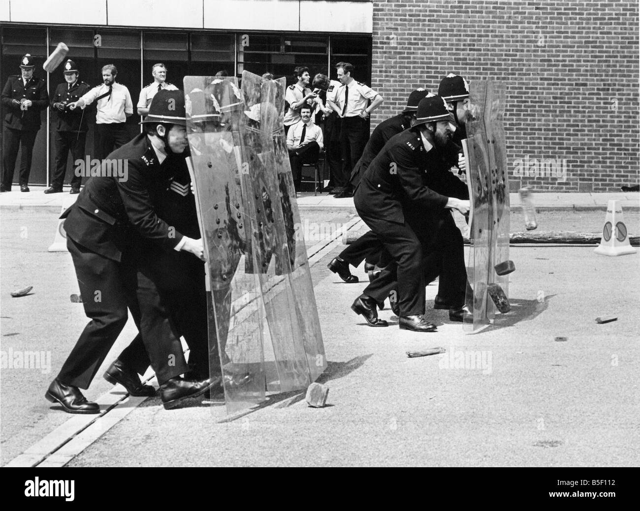 Formazione di base 1978 stile cadetti di polizia impara a trattare con una sommossa situazione cadetti di polizia a proteggersi contro i mattoni e macerie attacco Foto Stock