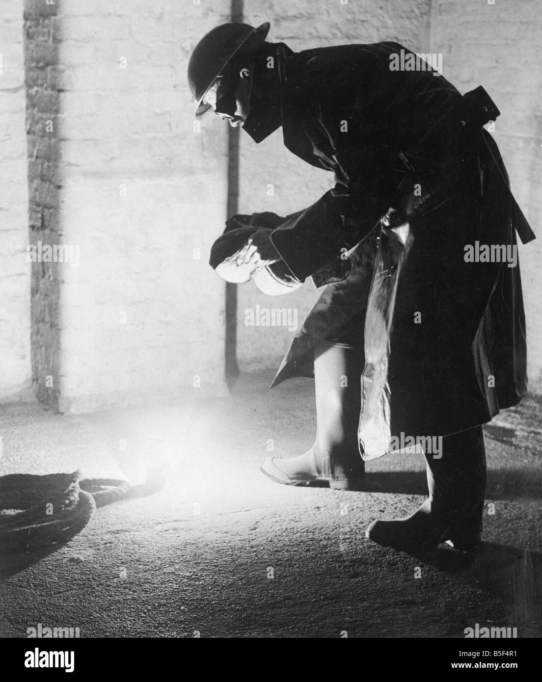 Un vigile del fuoco affronta una bomba incendary con un contrappeso che protegge il suo volto da blast.&#13;&#10;4 Maggio 1941 Foto Stock