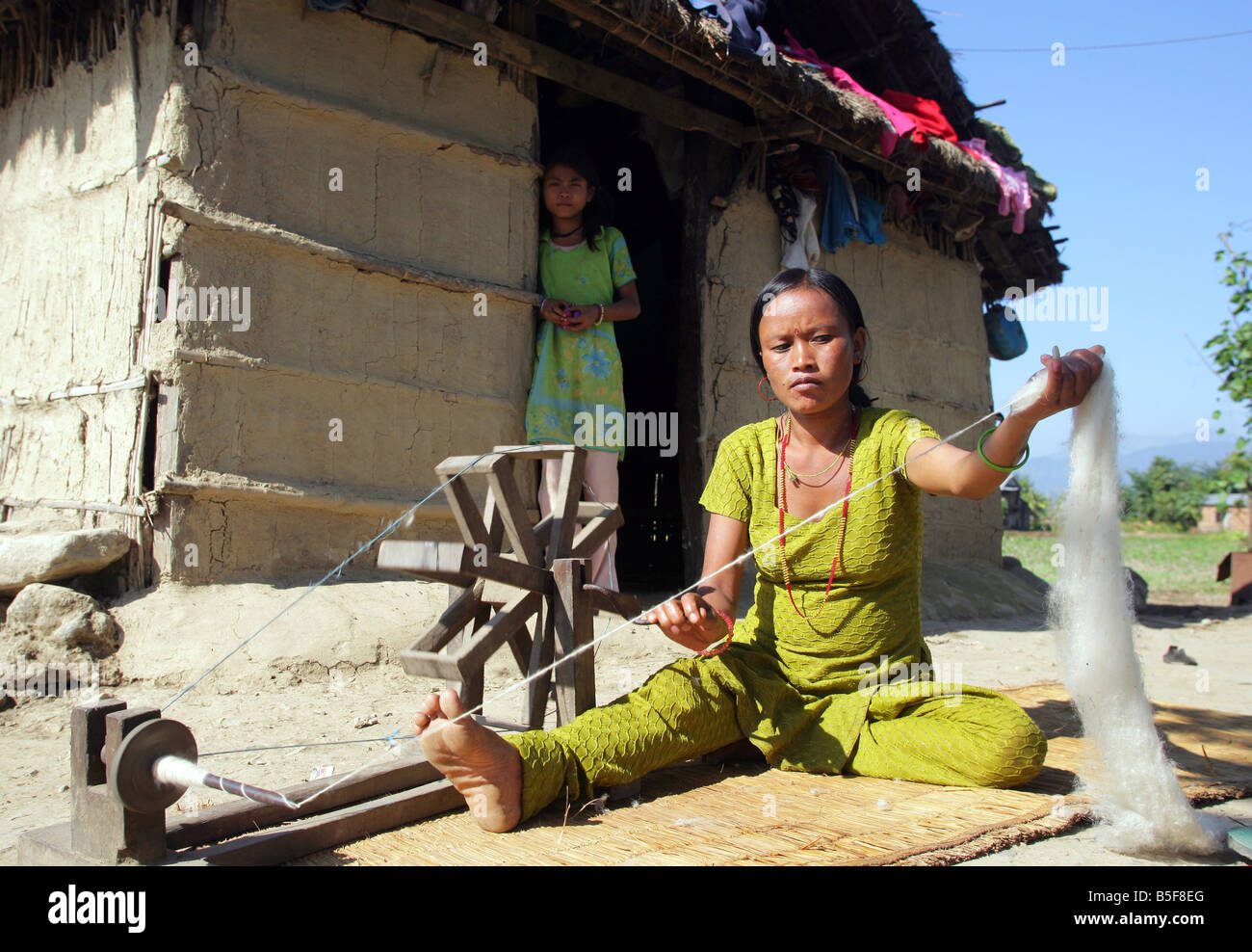 Il Nepal, donna gira il cotone sulla sua ruota di filatura Foto Stock