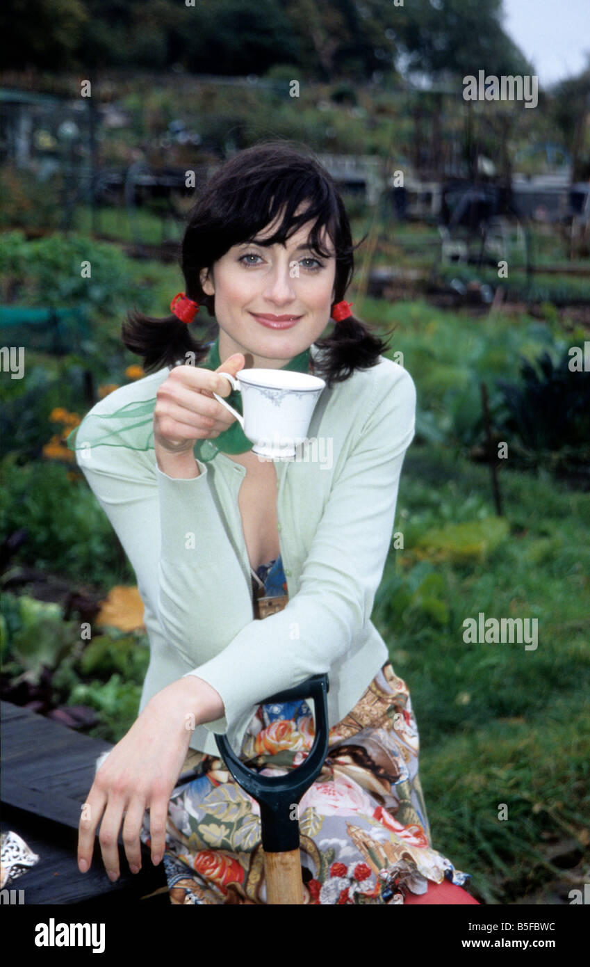 Una giovane donna con il tè e i biscotti in allotment Foto Stock