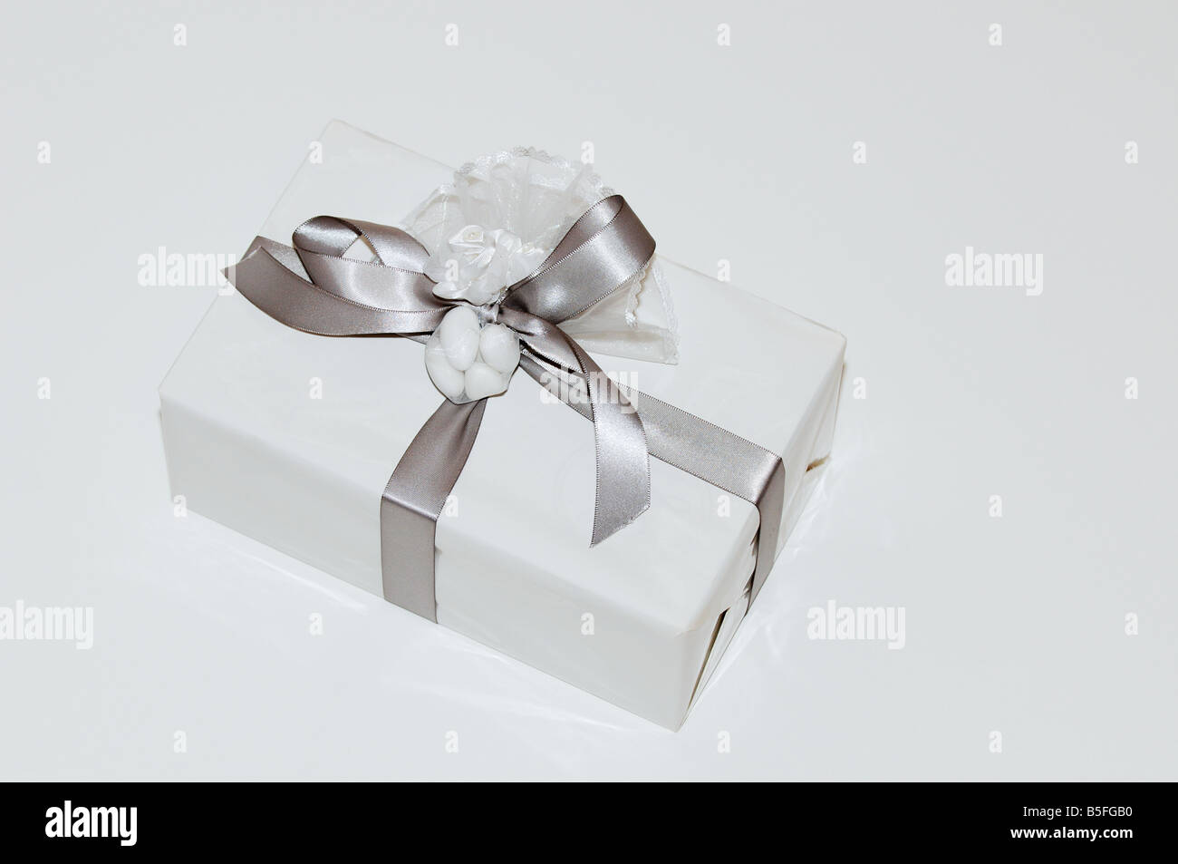 White gift wrapped box con arco di argento e nastro di sfondo bianco Foto Stock