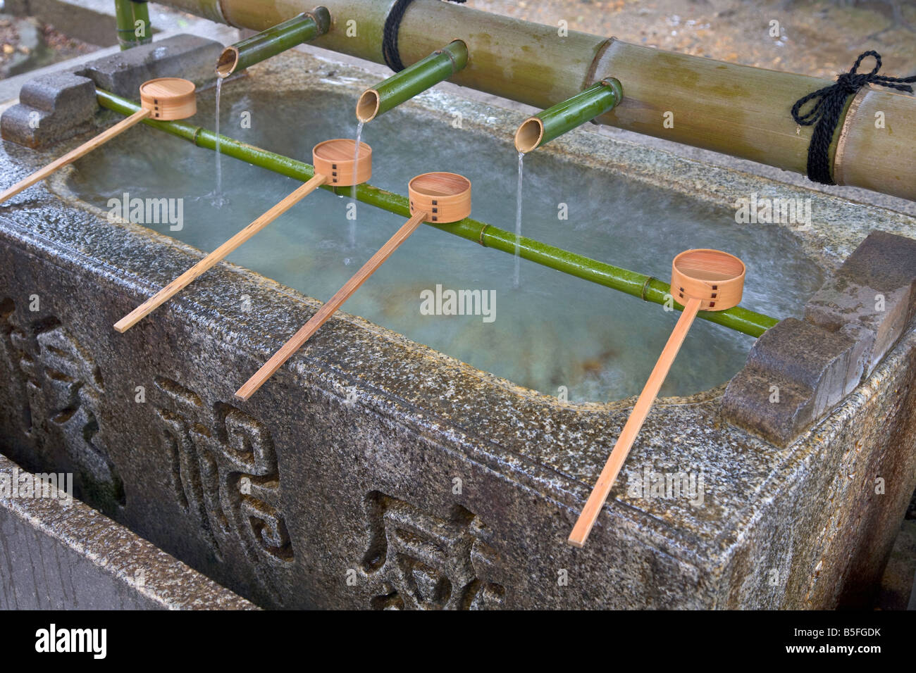 Siviere di bambù in appoggio sul rack hishaku oltre un chuzua lavaggio rituale trogolo di acqua in corrispondenza di Yasaka Santuario scintoista città di Kyoto in Giappone Foto Stock