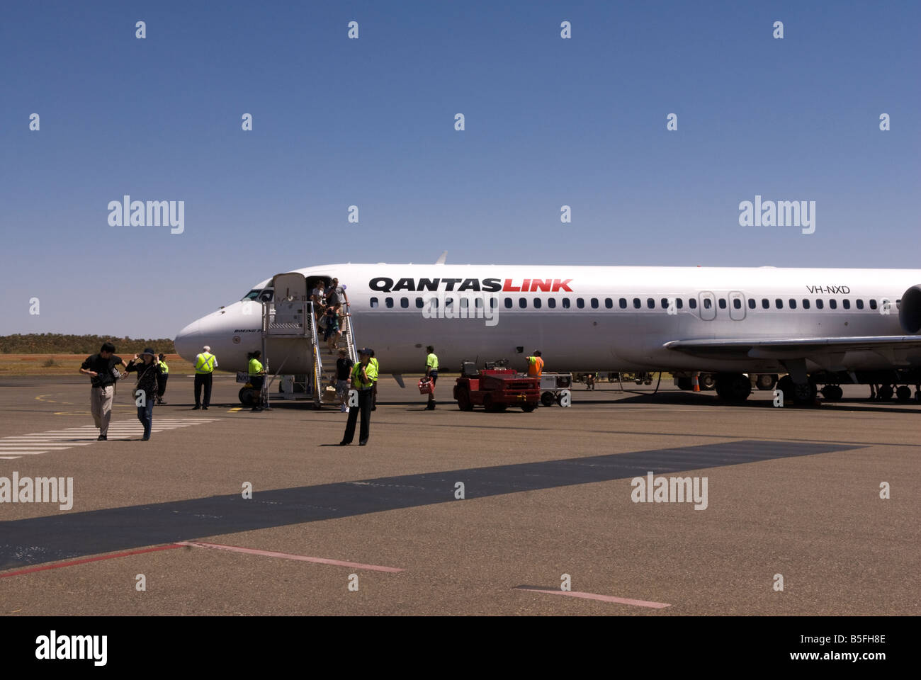 Sbarcare passeggeri di un aereo a Uluru Ayer's Rock aeroporto, Australia e attraversare a piedi per il terminale Foto Stock