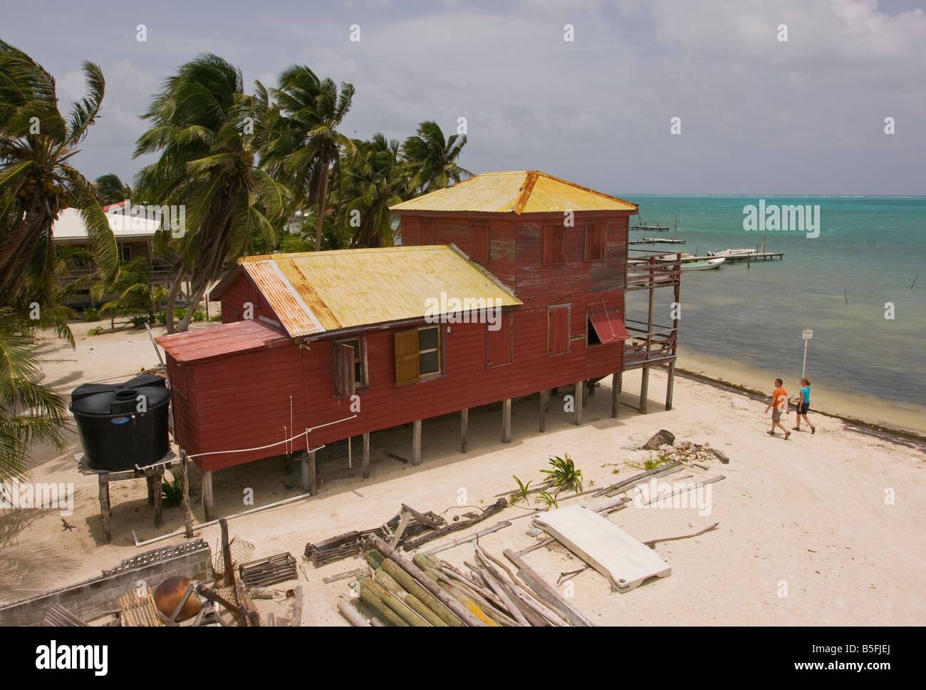 CAYE CAULKER BELIZE - Giovane passeggiate lungo la spiaggia da casa su palafitte. Bacino di acqua sistema è sul retro del cottage. Foto Stock