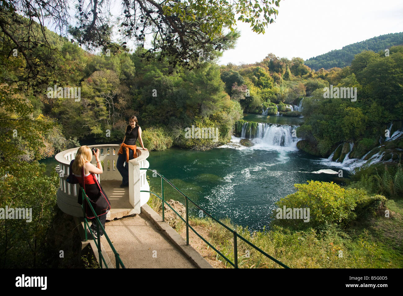 Ragazza tenendo la fotografia del suo amico che si affaccia il Skradinski Buk cascate del fiume Krka Parco nazionale di Croazia Foto Stock