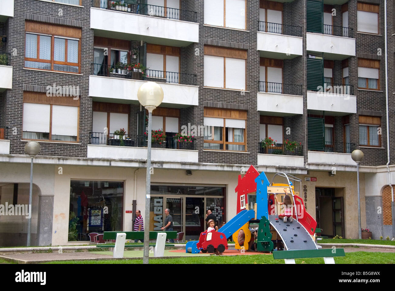 I bambini utilizzano attrezzature per parchi giochi nella parte anteriore di un appartamento unità di alloggiamento in Guernica Spagna settentrionale Foto Stock