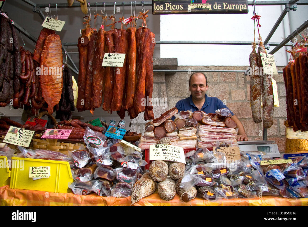 Venditore a vendere salumi presso un mercato all'aperto nella città di Cangas de Onis Asturias Spagna settentrionale Foto Stock