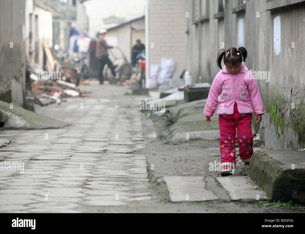 Un giovane annoiato ragazza asiatica andando lungo una parete, Suzhou, Cina Foto Stock