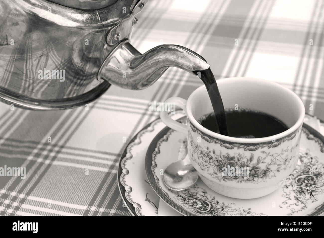 Versare fuori di riempire un bicchiere con un fresco e caldo caffè nero da un vecchio svedese POT del caffè realizzato in rame b/w Foto Stock