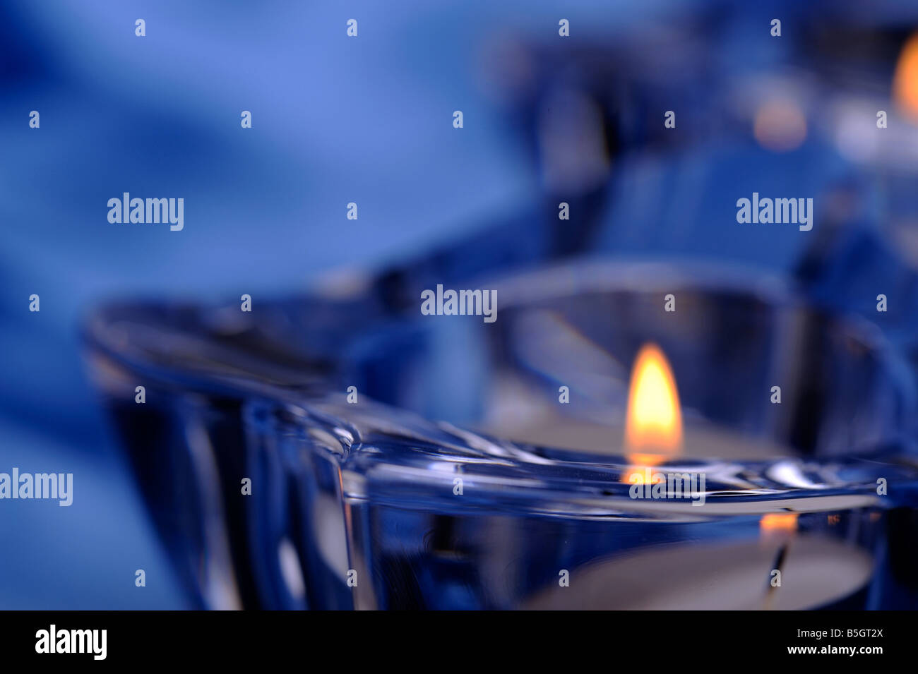 Coppia di candele in un candelieri in vetro blu sullo sfondo di seta Foto Stock