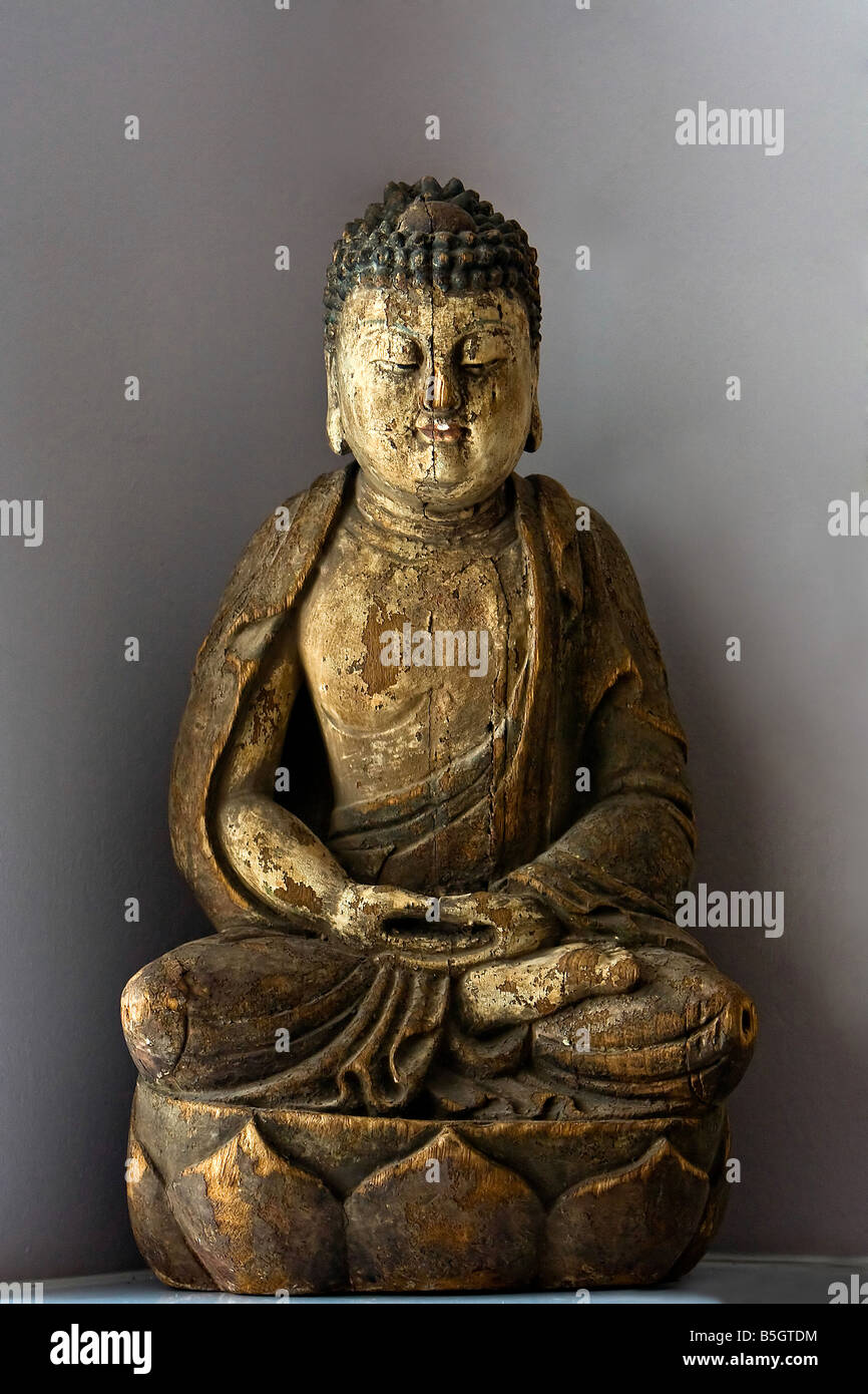 Una statua in legno del Buddha seduto nella posizione del loto isolato su grigio Foto Stock