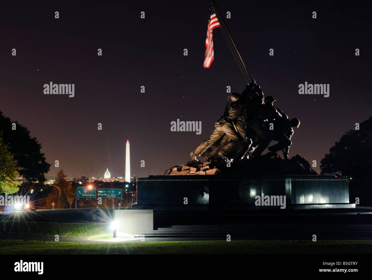 Iwo Jima Memorial durante la notte con il Monumento a Washington e il Capitol Building che brilla in background. Foto Stock