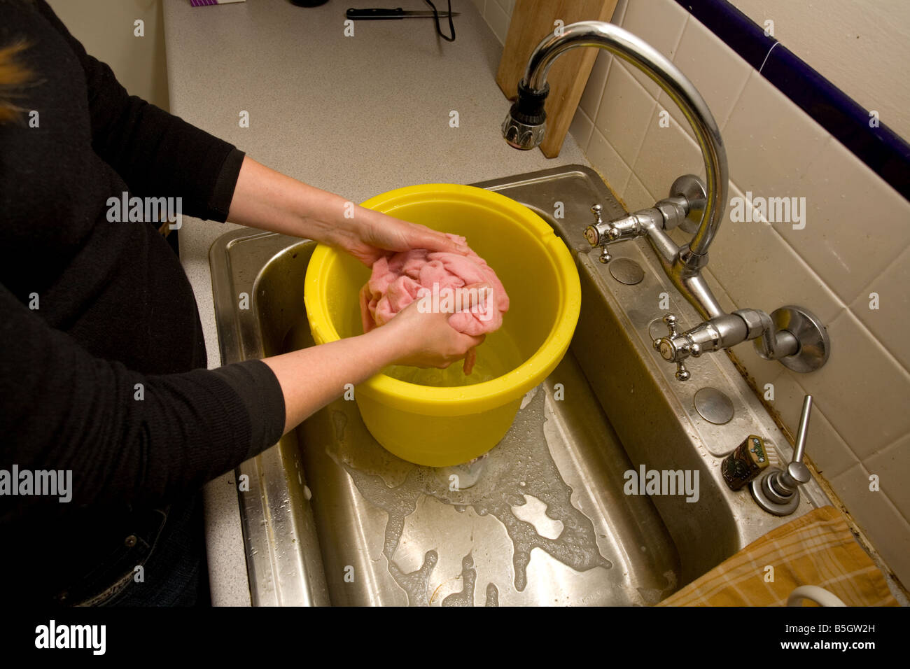 Donna lavaggio a mano vestiti nel lavandino Foto stock - Alamy