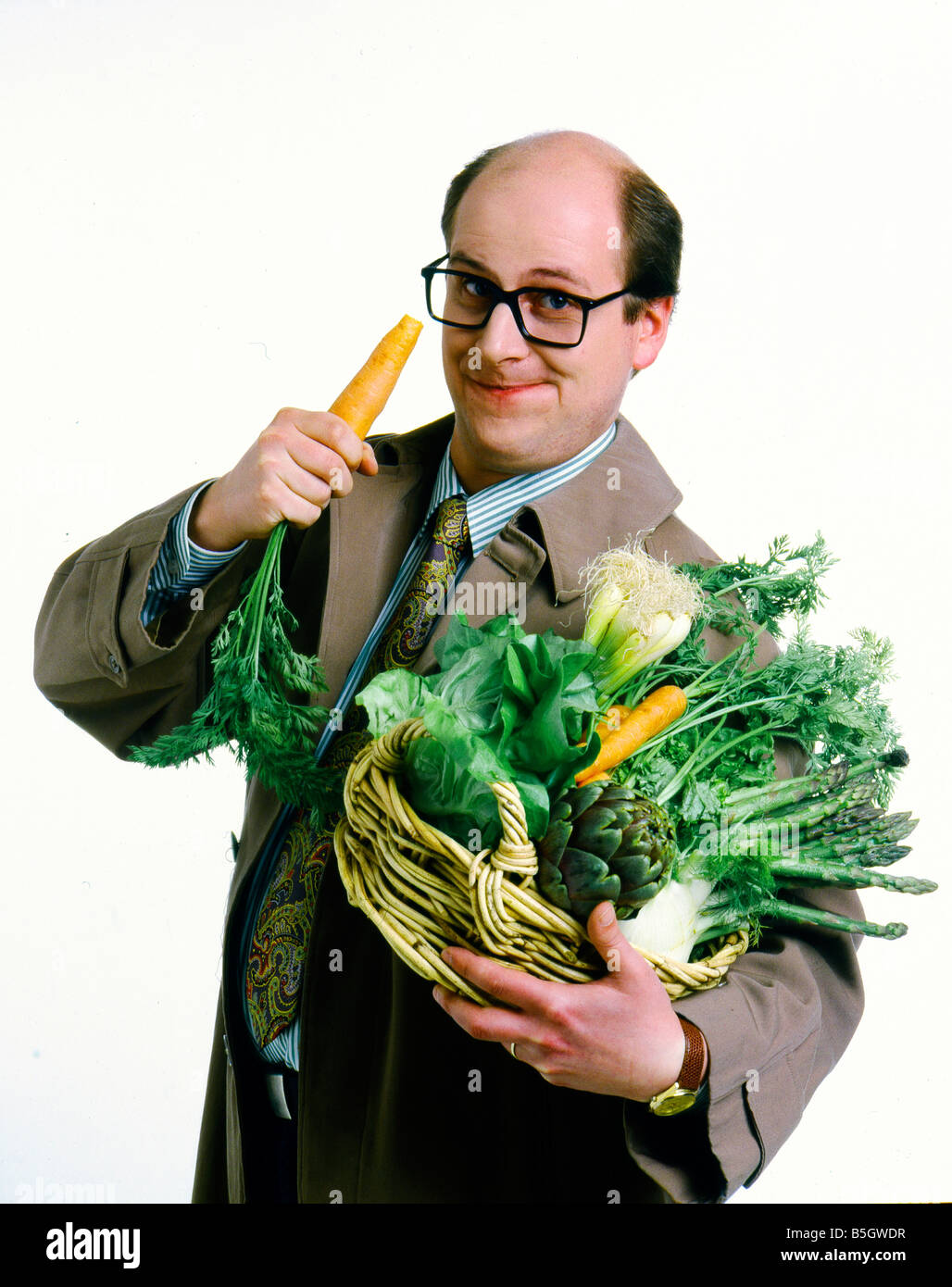 Uomo con un cesto di verdure nel suo braccio vengono a mangiare una carota Foto Stock