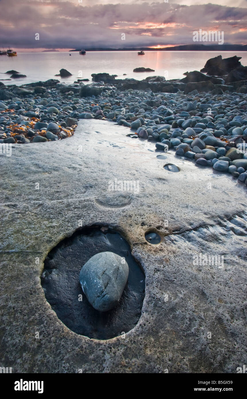 Incredibile eroso lastre di pietra calcarea e ciottoli sulla spiaggia Elgol, con il porto in background. Foto Stock