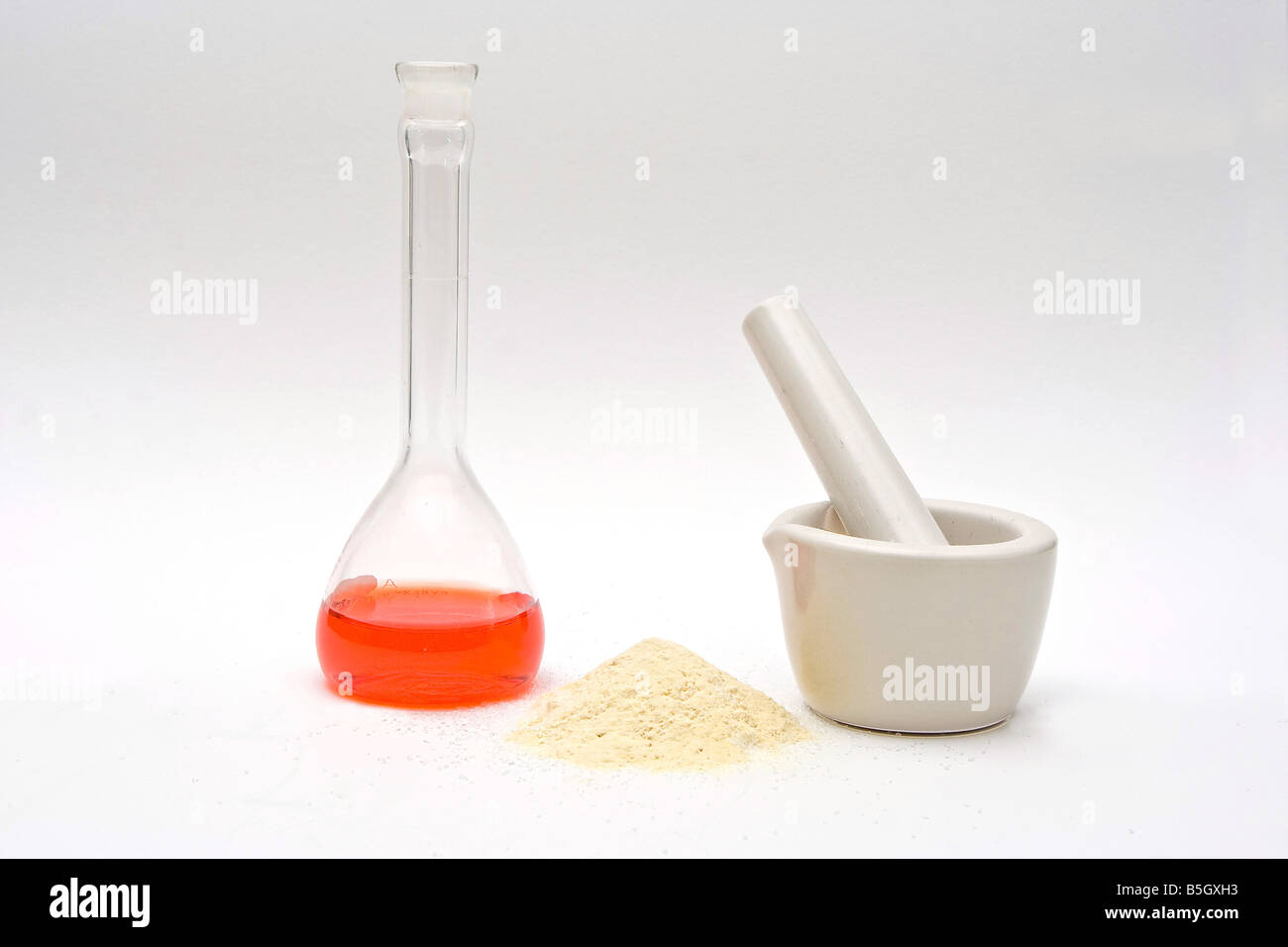 Un liquido rosso in un pallone con una polvere nella parte anteriore e un mortaio bianco su sfondo bianco Foto Stock