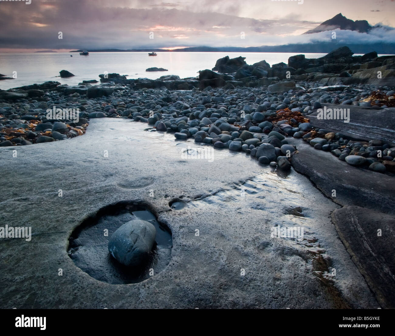 Incredibile eroso lastre di pietra calcarea e ciottoli sulla spiaggia Elgol, con il porto in background. Foto Stock