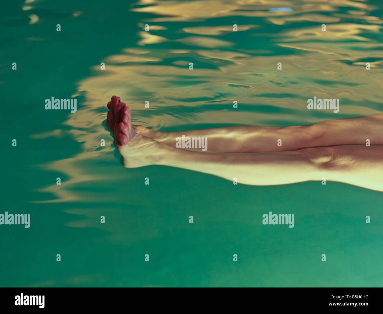 Gambe womans flottante in una piscina di acqua termale Foto Stock
