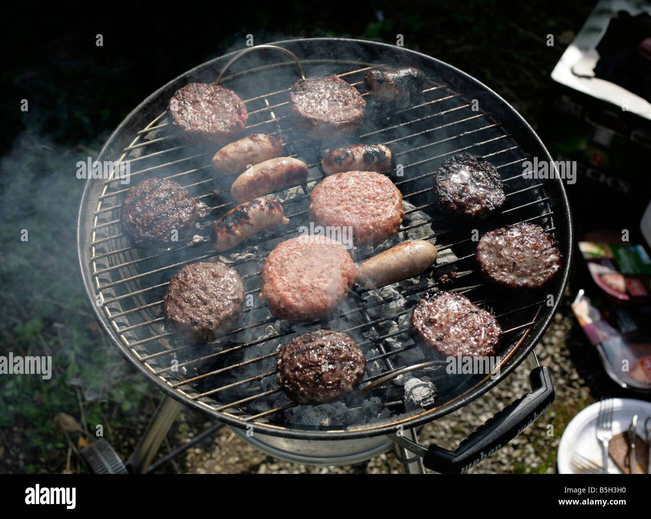 Gli hamburger e salsicce su un barbecue. Foto Stock