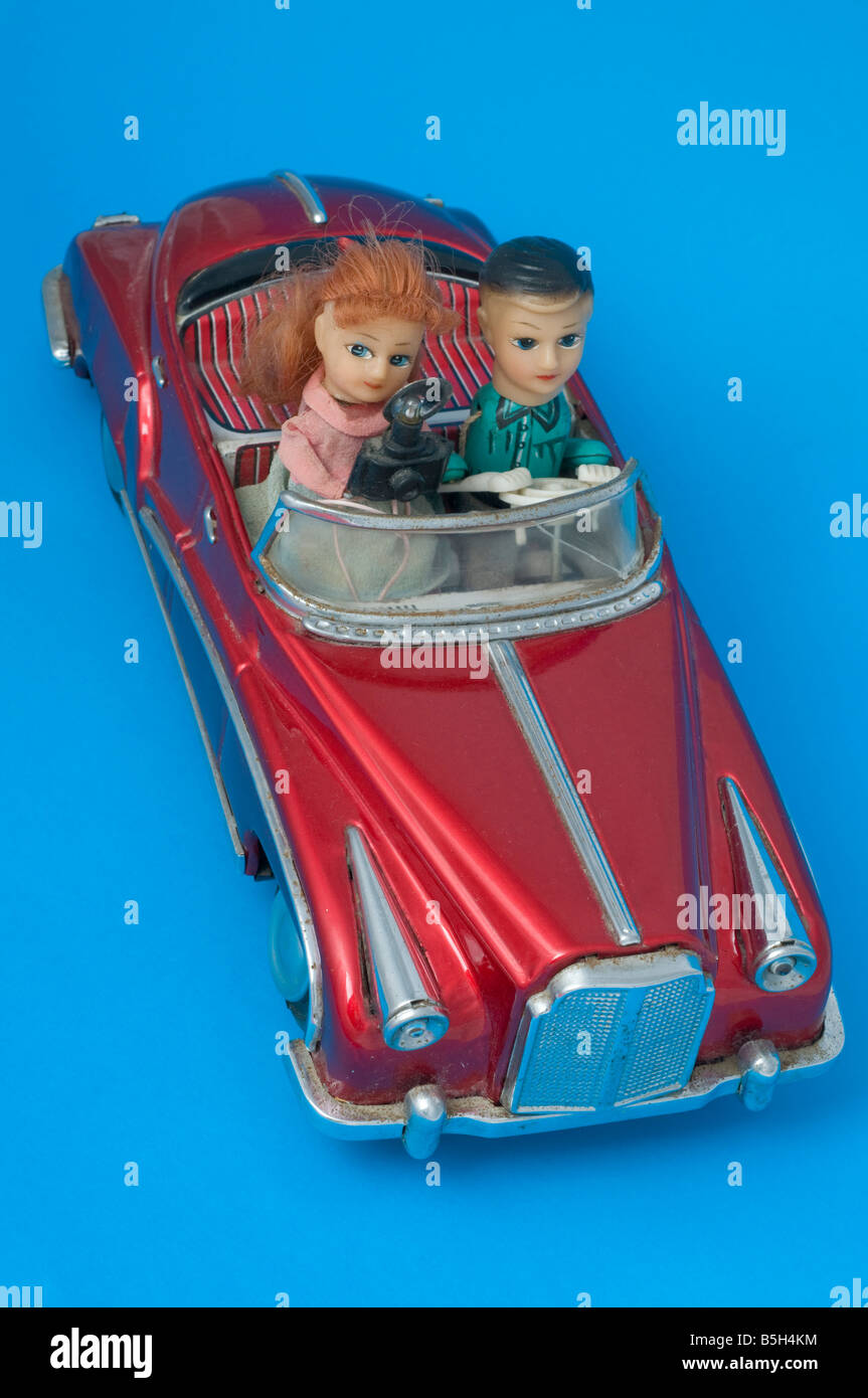 Auto alimentata a batteria giocattolo in metallo pressato con autista seduto accanto a una fotografa donna con fotocamera e flash. Foto Stock