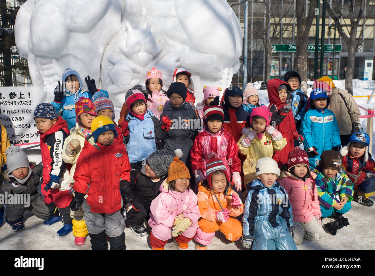 Sapporo Giappone Sapporo Snow Festival Parco Odori scuola bambini riuniti per una foto di fronte a grandi sculture di ghiaccio Foto Stock