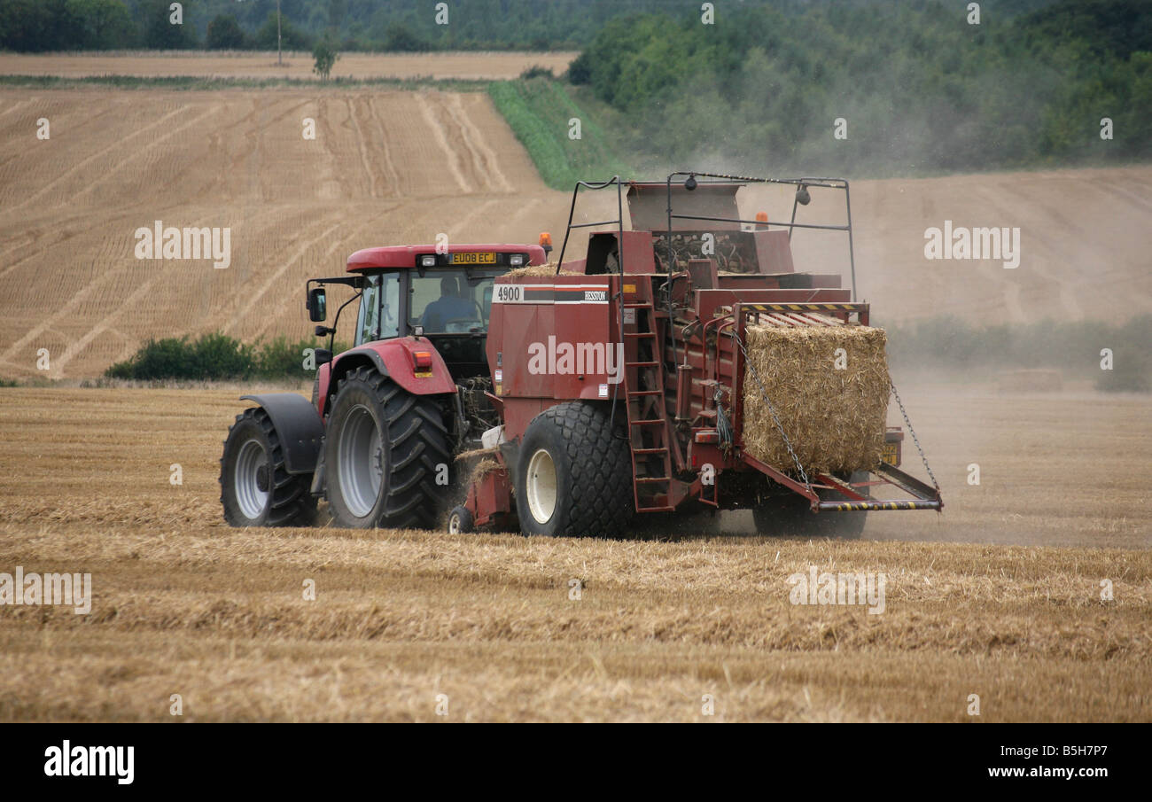 Un trattore rende bails di fieno sulle zone rurali e tra Clare e Cavendish in Suffolk Foto Stock