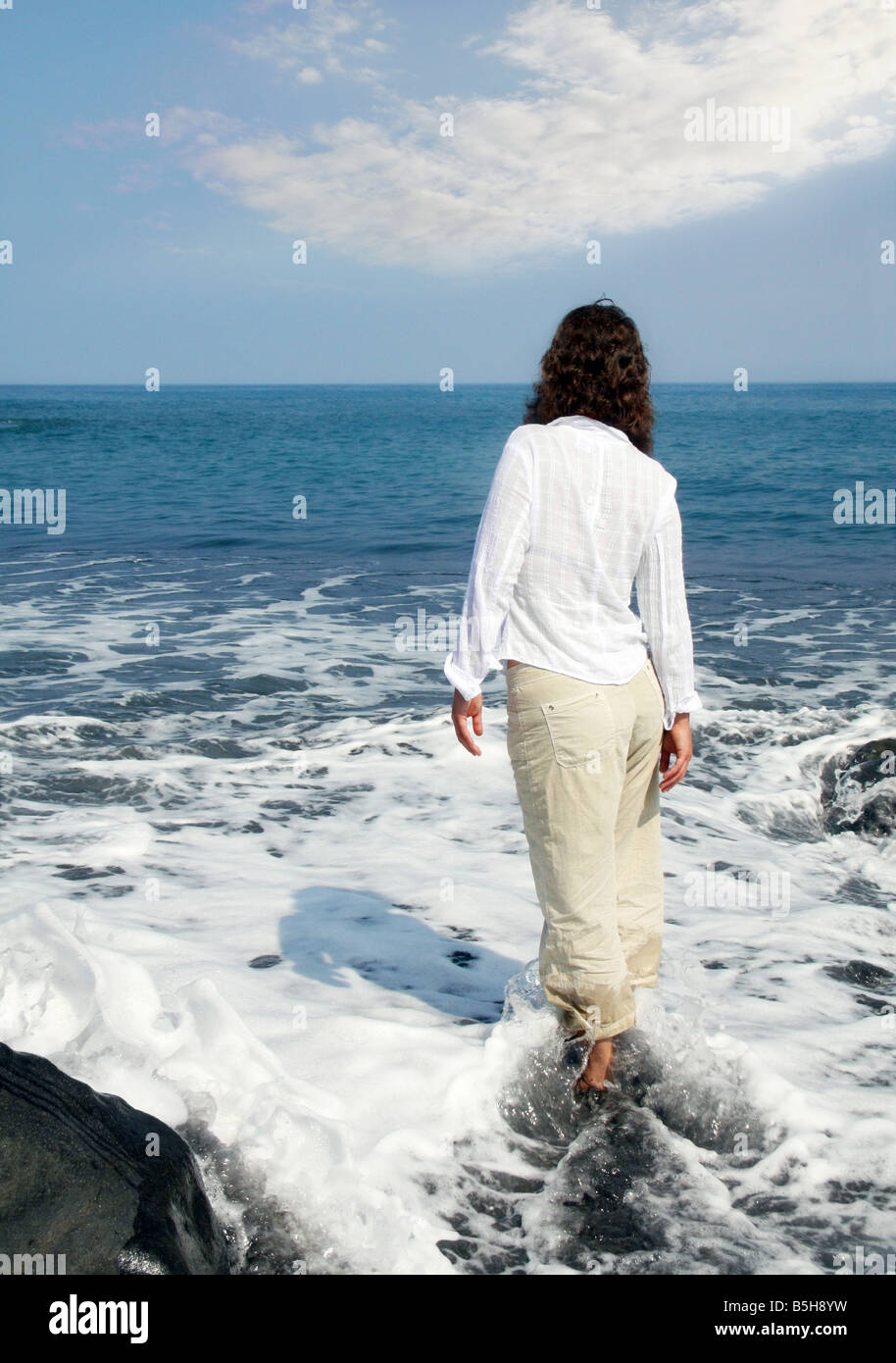 Donna in piedi su una spiaggia di sabbia nera sulla Big Island delle Hawaii Foto Stock