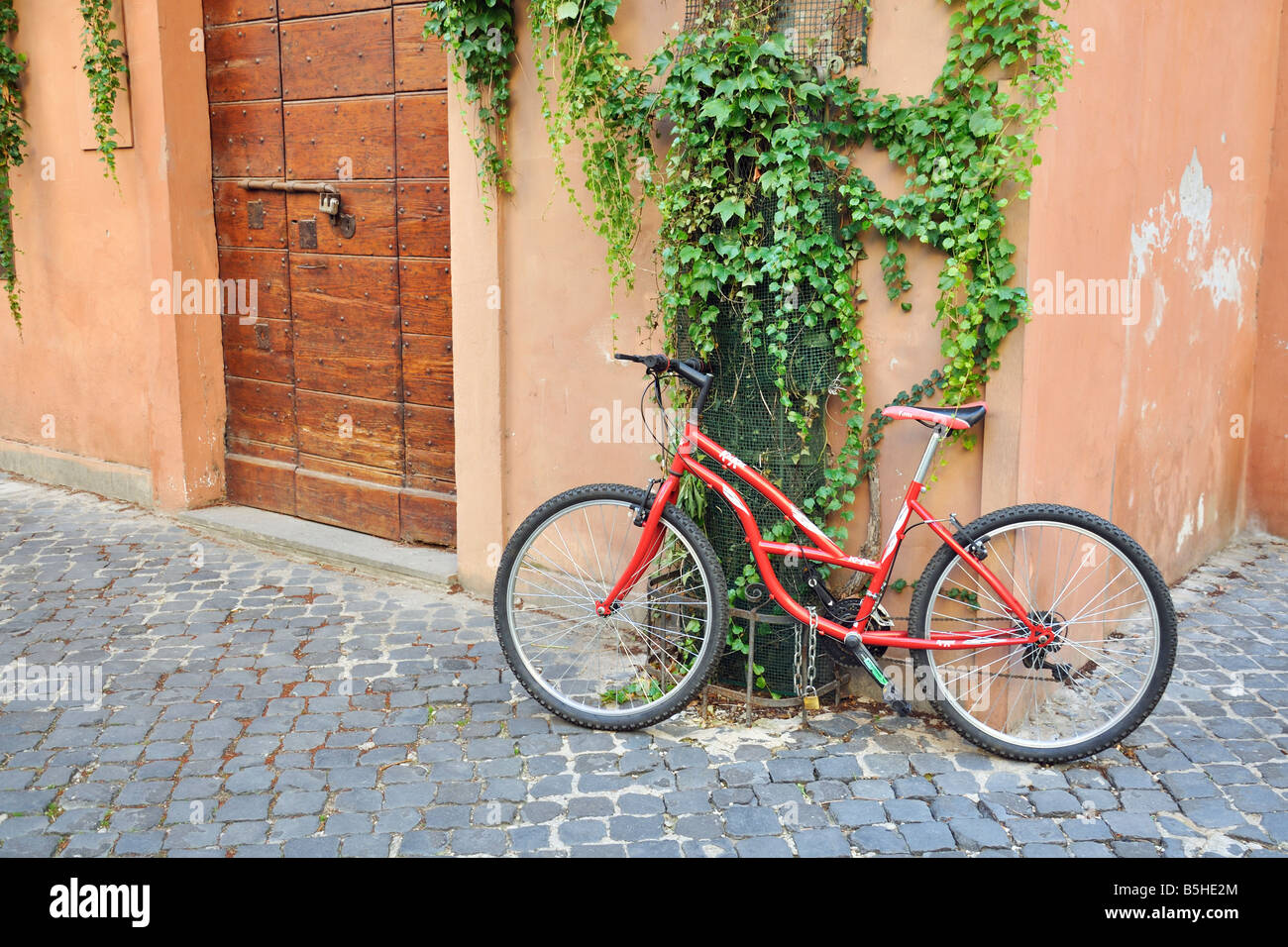 Una bicicletta incatenata al lato di una casa a Trastevere, una vecchia sezione di Roma. Foto Stock