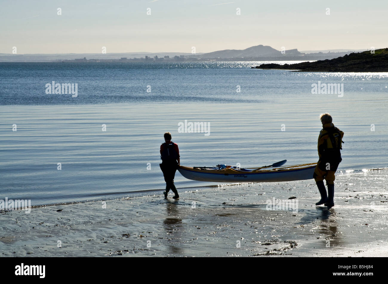 dh coppia Kayak canoe SPORT ACQUATICI KAYAK Regno Unito SCOZIA due donne sulla spiaggia che porta canoa alle acque bordo mare sport 2 persone Foto Stock