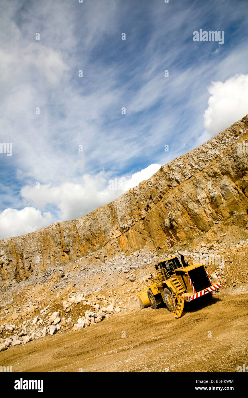 Un immagine angolata di un grande bulldozer lavorando in una cava di estrazione di pietra sotto un cielo blu Foto Stock