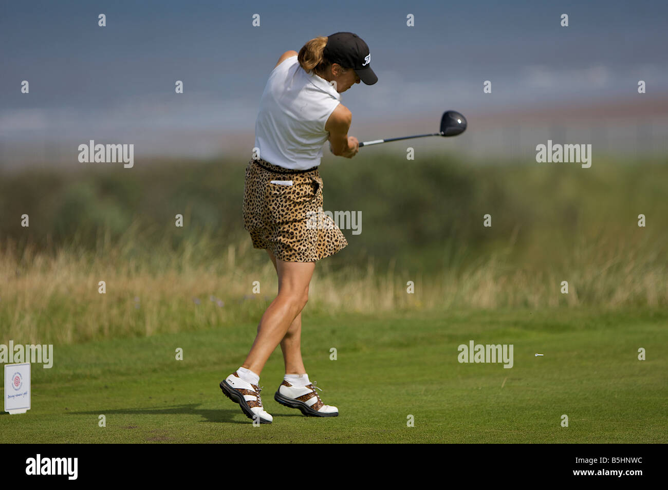 Signora golfista guida off lungo il fairway Foto Stock