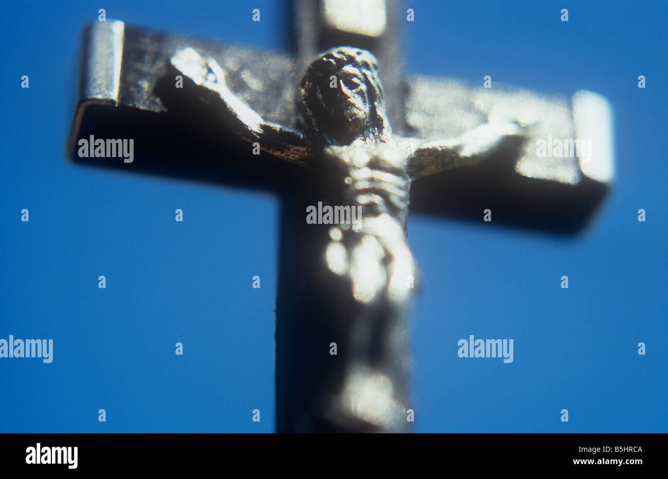 Modello argento di Gesù Cristo pendente dal nero crocifisso ligneo con tappi in argento contro il cielo blu chiaro Foto Stock