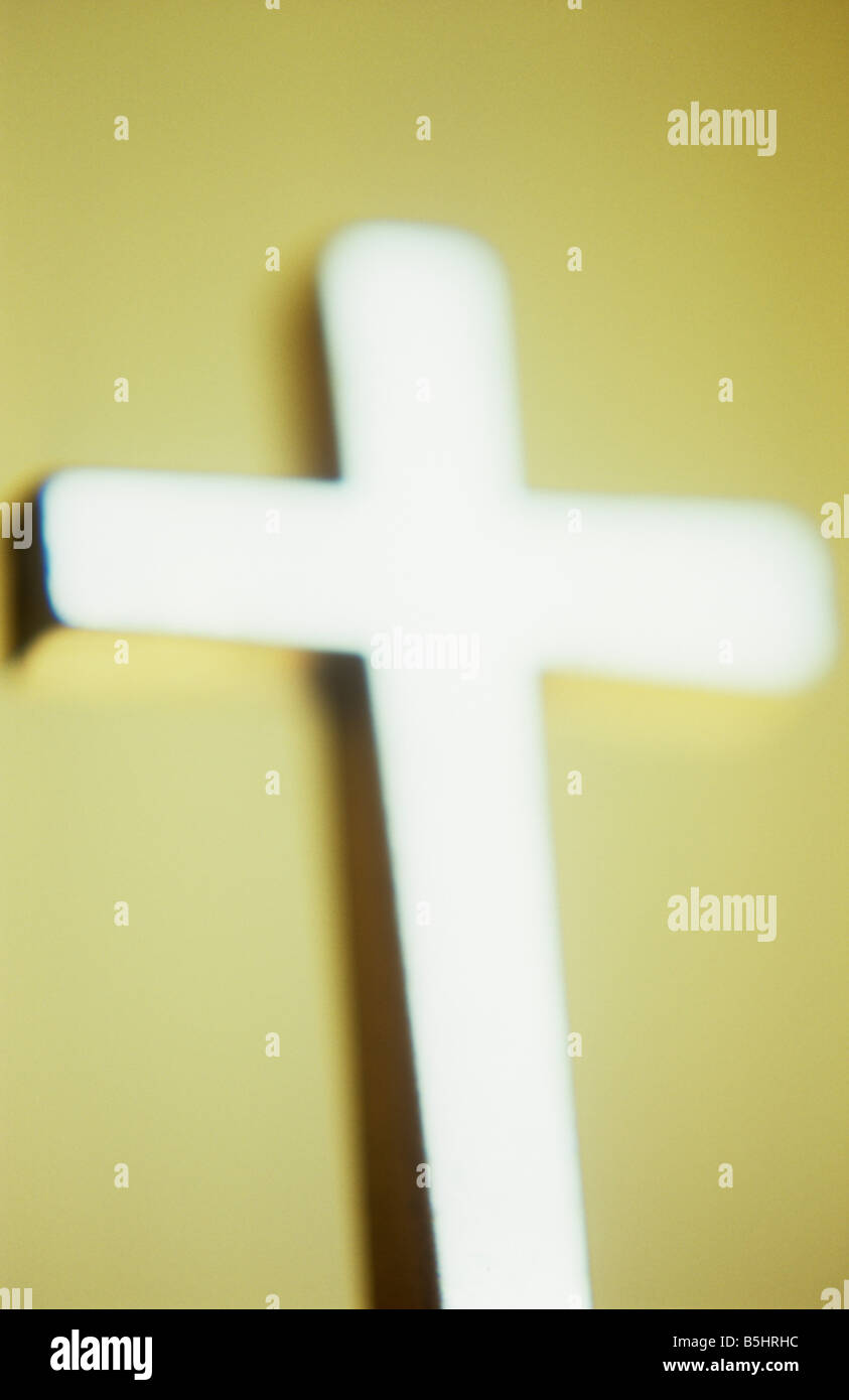 Impressionistica crocifisso di argento nella parte anteriore della crema parete dipinta e pulsa con la brillante luce riflessa Foto Stock