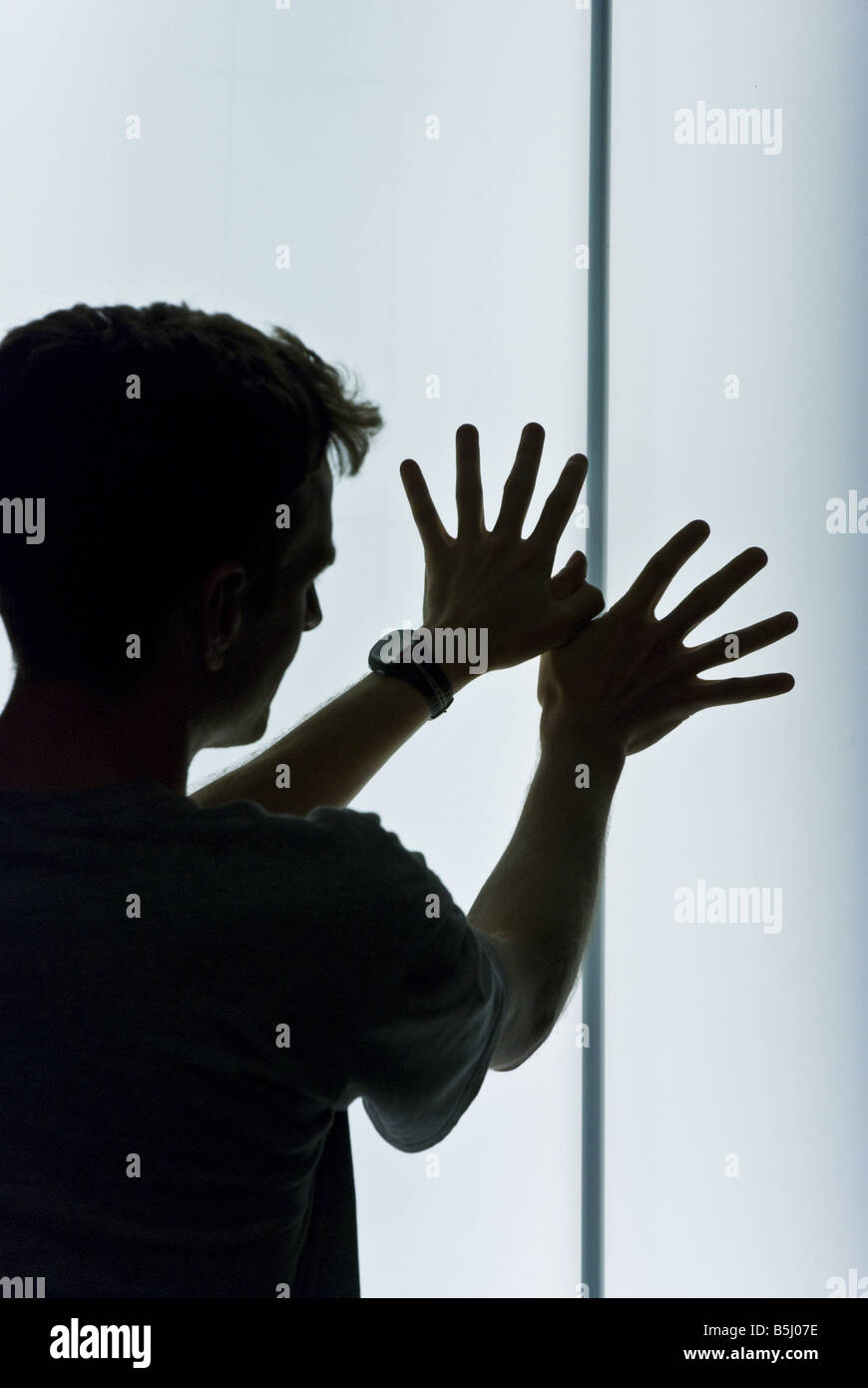 Un uomo fa una farfalla simbolo in silhouette di fronte a un pilastro illuminato in Anversa stazione ferroviaria nei Paesi Bassi. Foto Stock