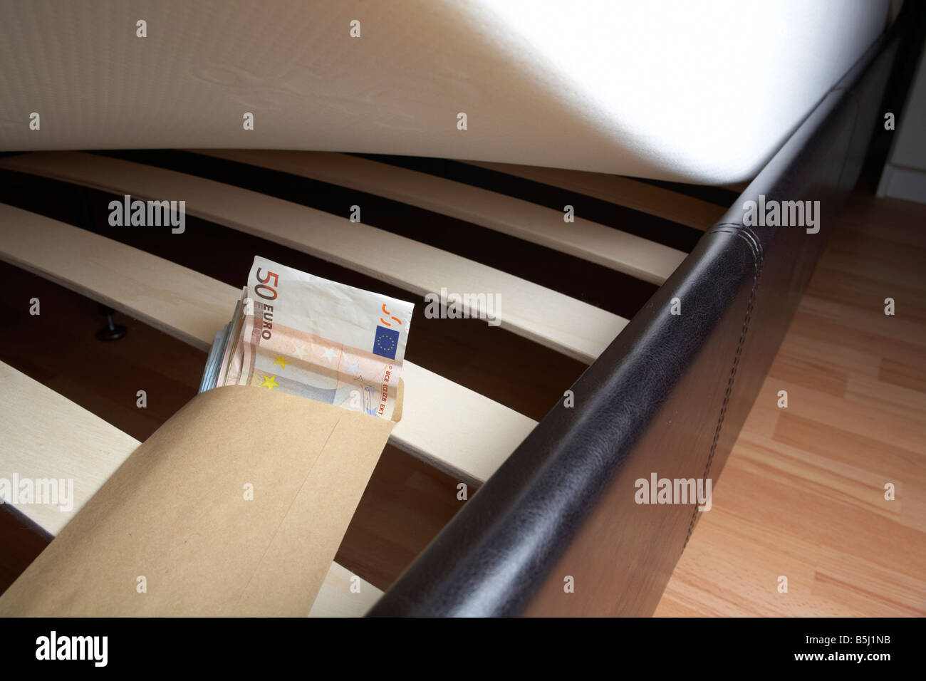 Borra di 50 20 e 10 le banconote in euro di contanti in una busta ripiene sotto il materasso di un letto Foto Stock Borra di 50 20 e 10 le banconote in euro di contanti in una busta ripiene sotto il materasso di un letto Foto Stock