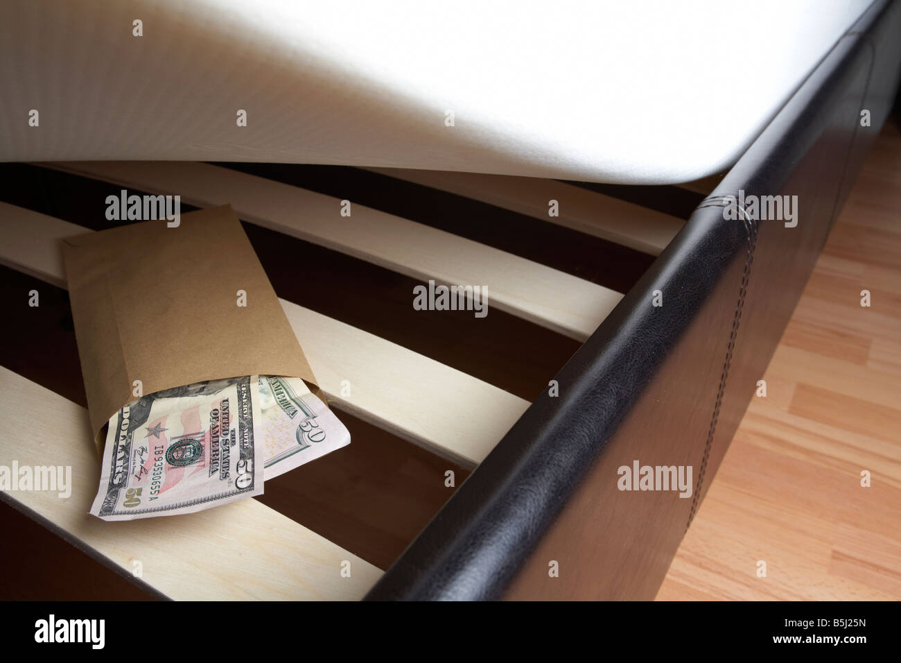 Borra di noi 50 dollar note di contanti in una busta ripiene sotto il materasso di un letto Foto Stock