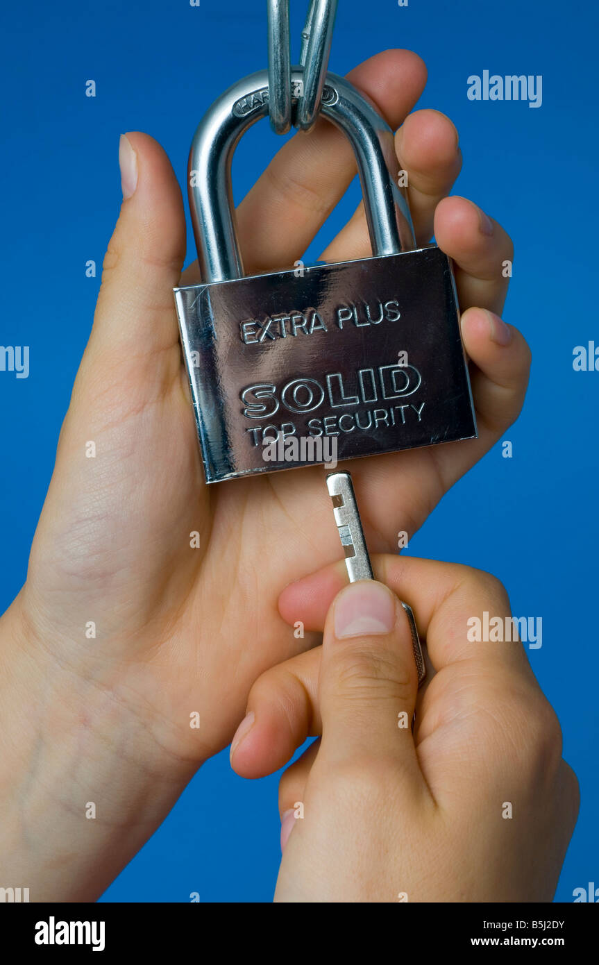 Mani che fissano un lucchetto resistente con la chiave Foto Stock