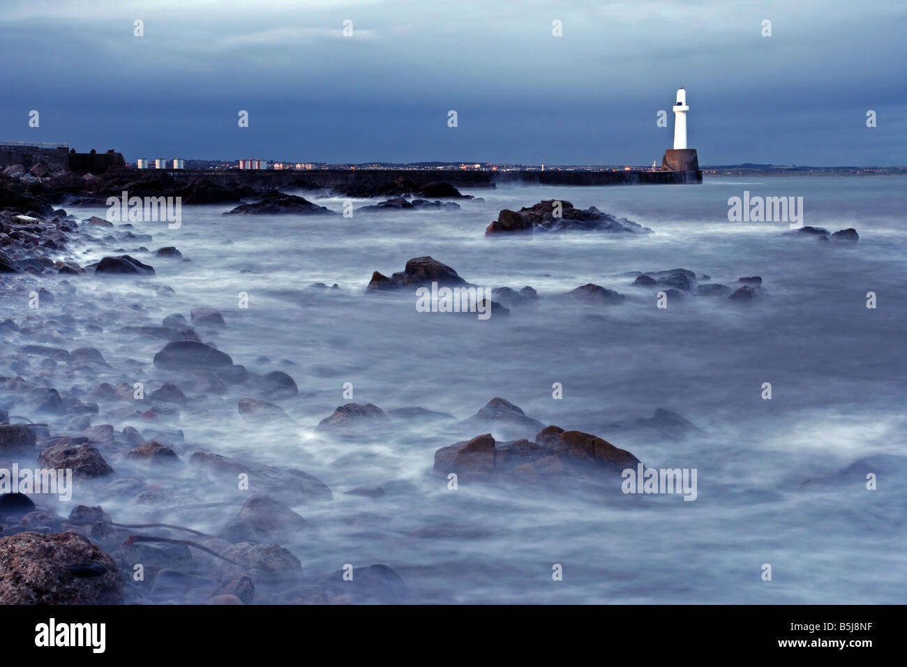 La diga sud e il faro all'entrata del porto di Aberdeen, Scozia, visto al tramonto. Foto Stock