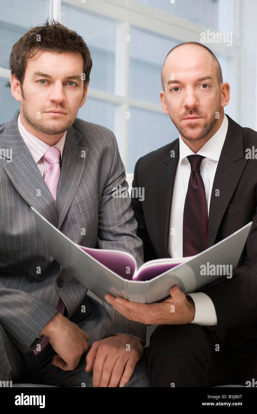 Due imprenditori seduti insieme documento di lettura Foto Stock