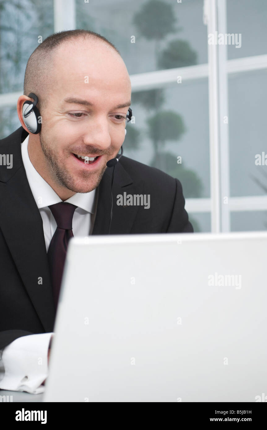 Ritratto di imprenditore che indossa la cuffia funziona con computer portatile Foto Stock