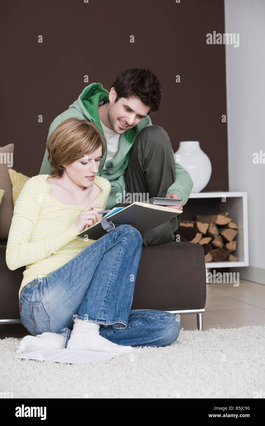Coppia giovane la lettura dei documenti a casa insieme Foto Stock