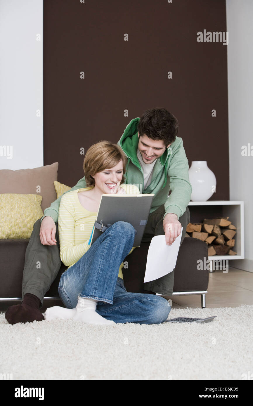 Coppia giovane la lettura dei documenti a casa insieme Foto Stock