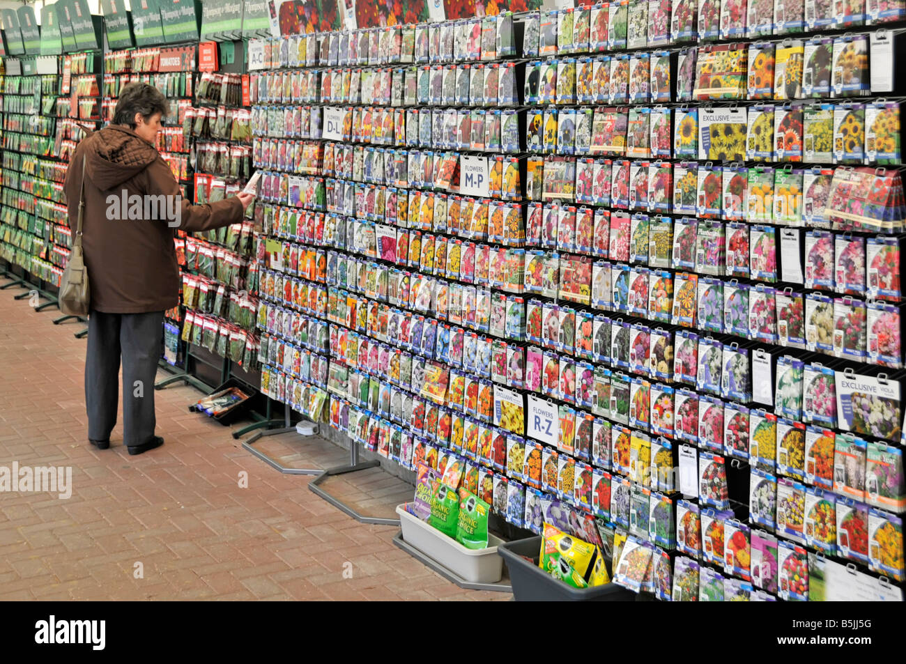 Donna shopping per i pacchetti di sementi in centro giardino Foto Stock