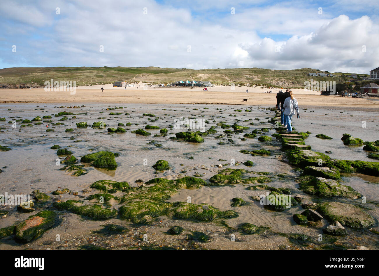 Camminare su pietre miliari attraverso un ruscello su Perran sands beach in Perranporth, Cornwall Regno Unito. Foto Stock