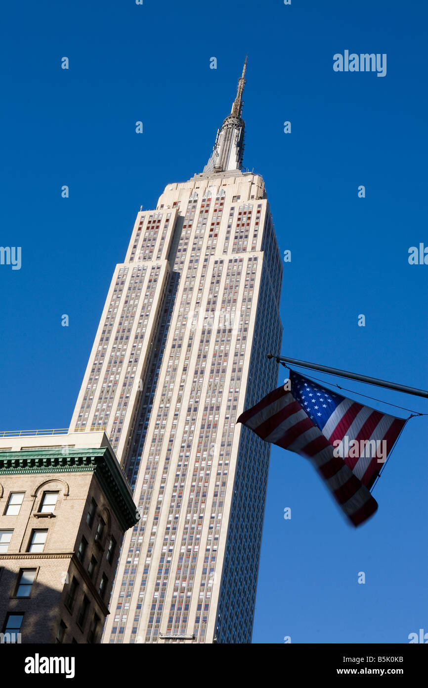 L'Empire State Building con stelle e strisce battenti nel vento, Fifth Avenue di New York City STATI UNITI D'AMERICA Foto Stock