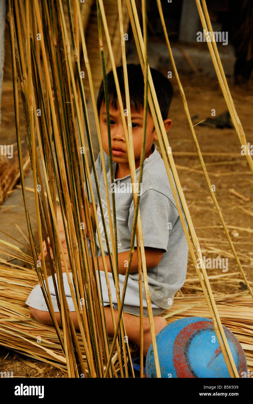 Ragazzo Balinese è giocare con erba essiccata,Bali, Indonesia. Foto Stock