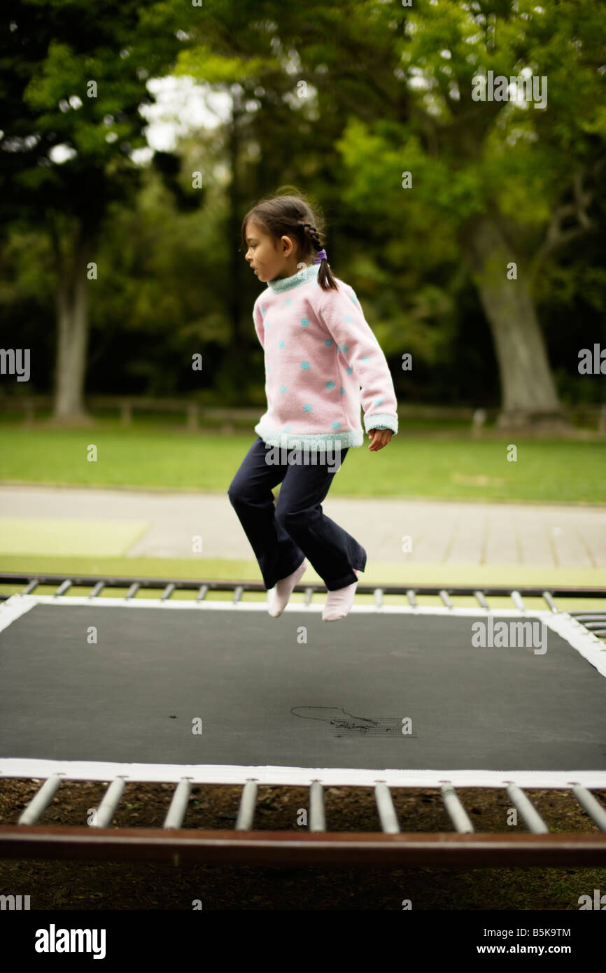 Bambina di cinque anni che rimbalza su un trampolino Foto Stock