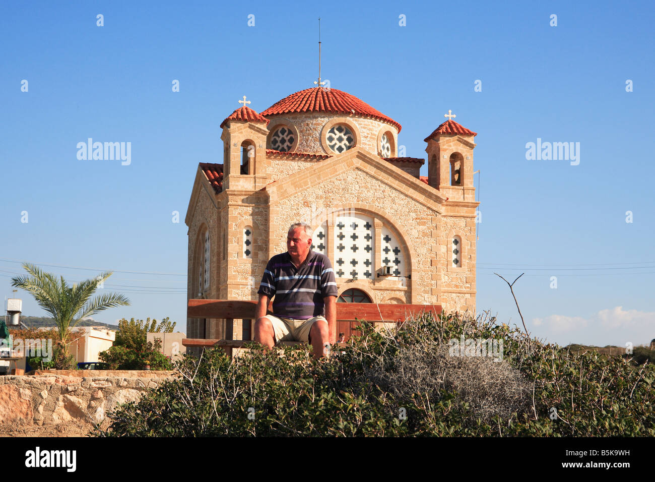 Uomo seduto sul bancone di Agios Georgios tis Pegeias chiesa sulla costa occidentale di Cipro Foto Stock